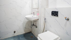 A bathroom with a white sink, a toilet, and a shower area. - HOTEL CAPITOL SQUARE (Jaipur)
