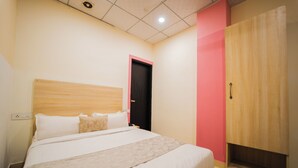A hotel room with a bed, a wardrobe, and a door. - HOTEL CAPITOL SQUARE (Jaipur)