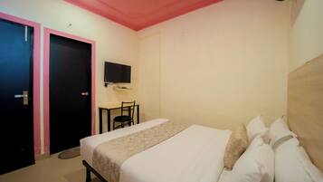 A hotel room with a bed, a desk, a chair, a television, and a ceiling fan.
