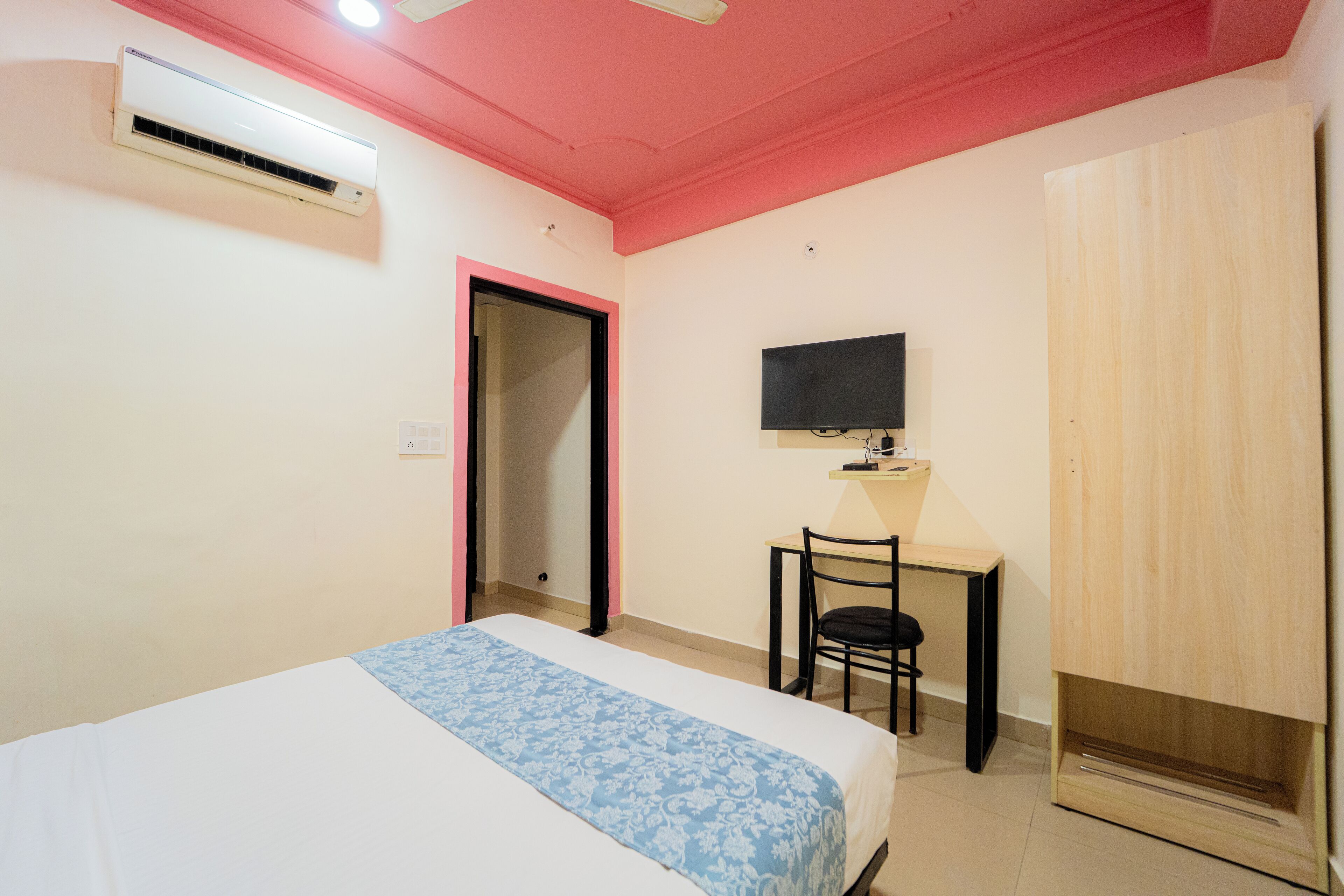 A bedroom with a bed, a desk, a chair, a TV, and a wardrobe.