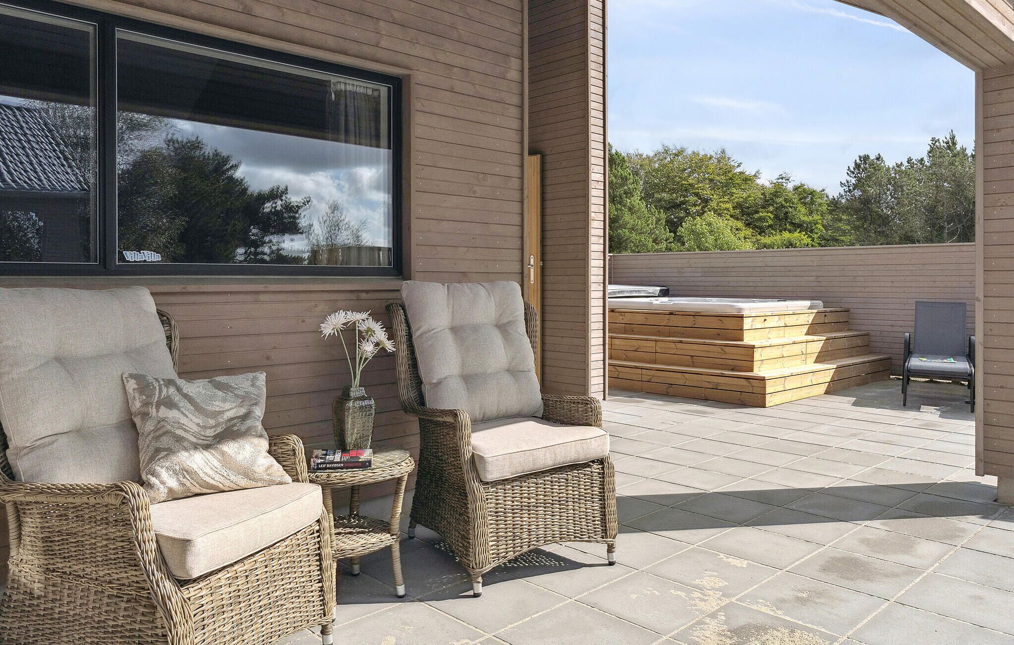 Een terras met rieten meubilair, een jacuzzi en een houten terras.
