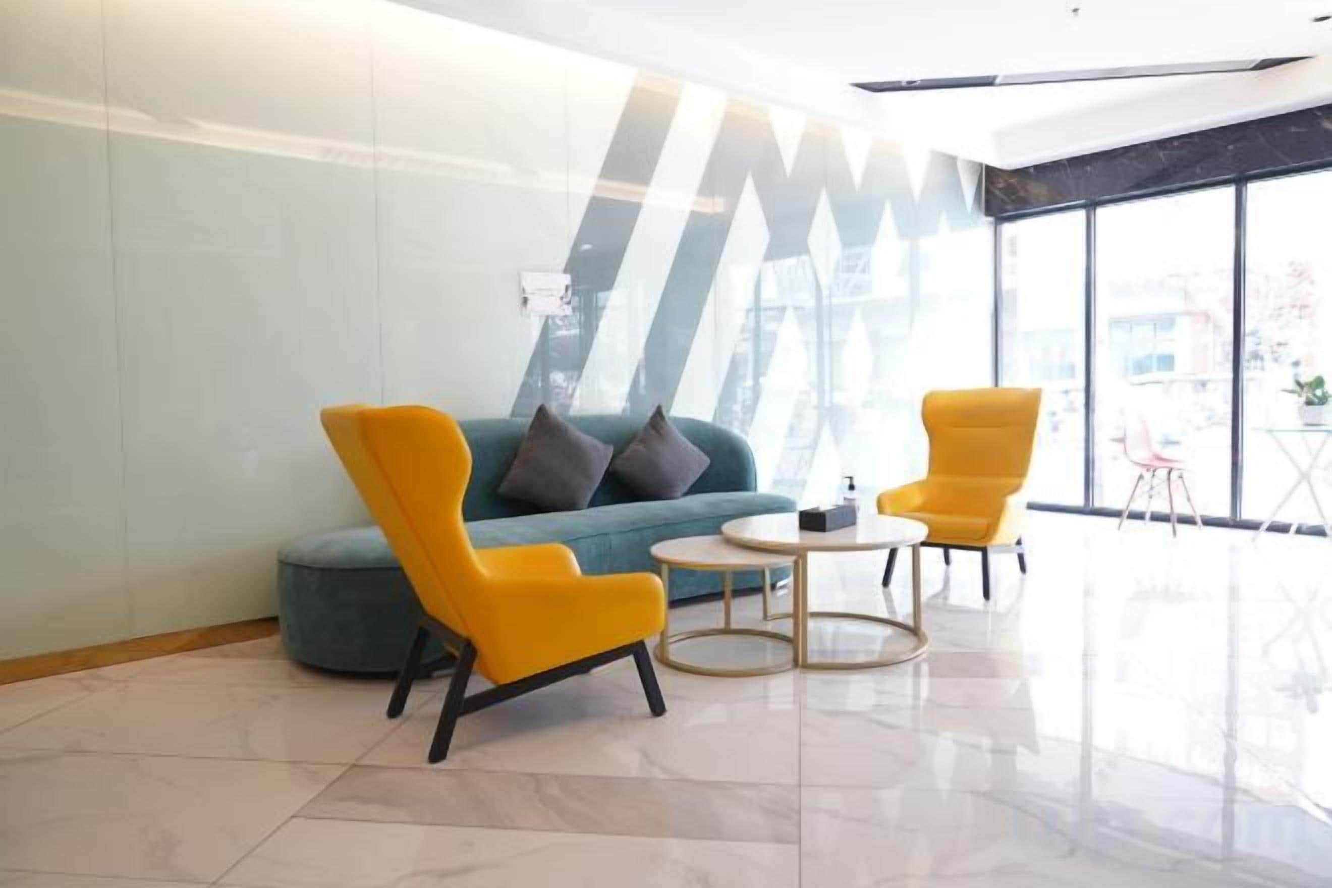 A modern lobby with a sofa, two armchairs, a round table, and large windows.