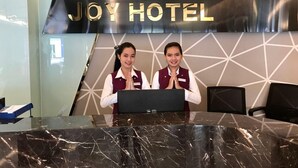 A reception desk at Joy Hotel with a marble countertop, framed photos above, and a geometric wall design. - Joy Hotel (Phnom Penh)