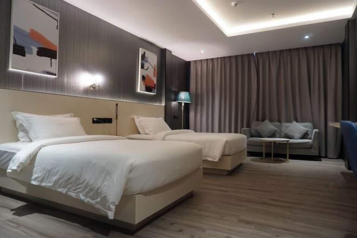 Une chambre d’hôtel moderne avec un grand lit, un canapé, une petite table et une lampe.