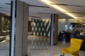 A modern lobby with a reception desk, seating area, and a patterned wall. - Joy Hotel (Phnom Penh)