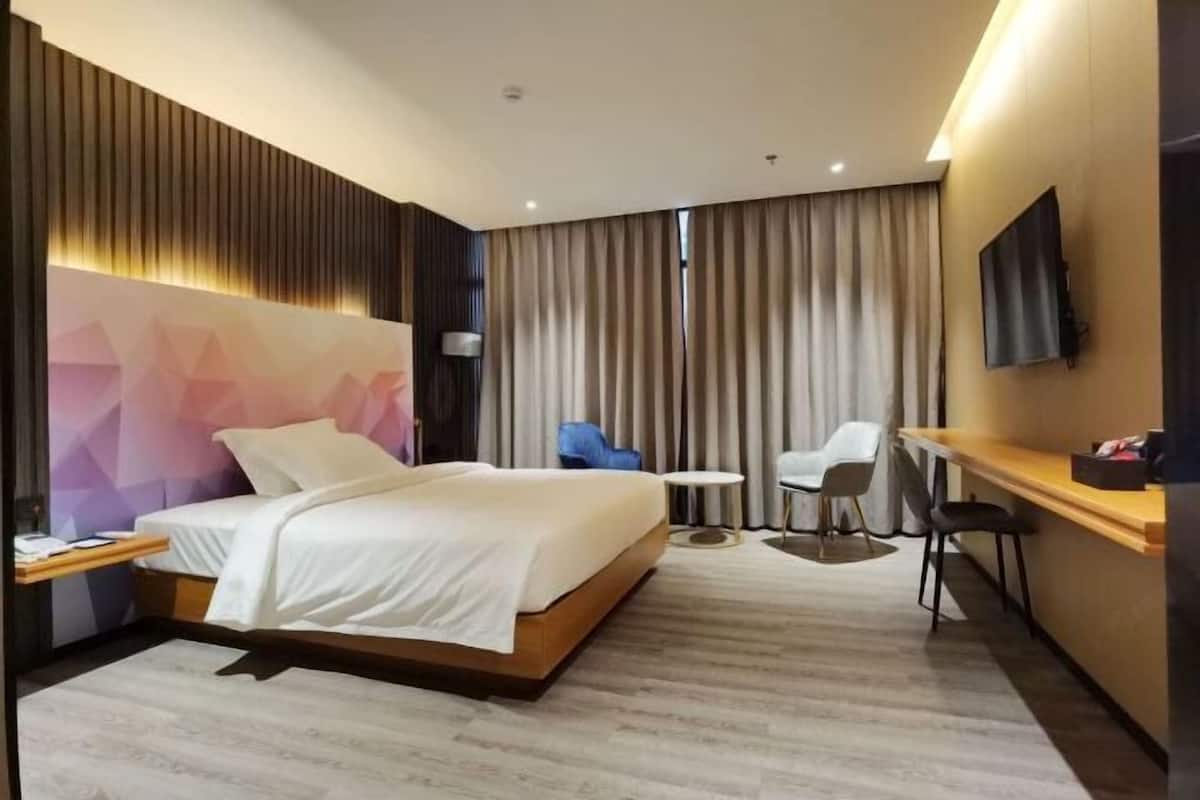 Une chambre d’hôtel moderne équipée d’un lit, d’un bureau, d’une chaise, d’une télévision et offrant une vue sur l ’extérieur.