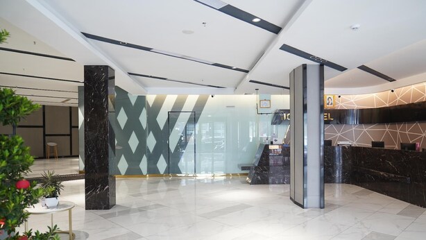 A modern hotel lobby with a reception desk, marble columns, and a geometric patterned wall. - Joy Hotel (Phnom Penh)