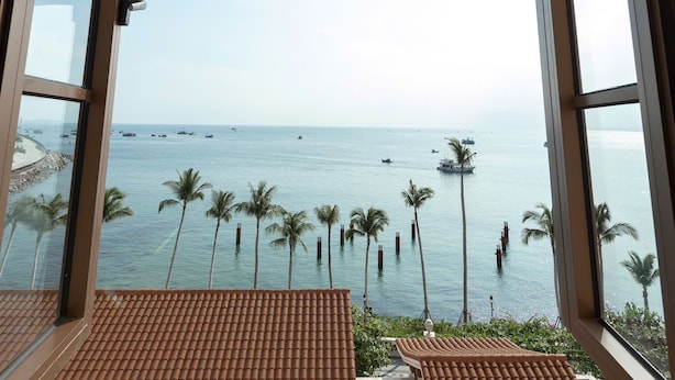 A view from a room with a tiled floor and a window overlooking a beach with palm trees and boats. - Lucie Cozy Home - Sunset Town Phu Quoc (Phu Quoc)