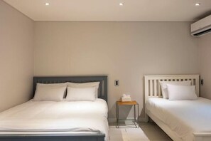 A hotel room with two beds, a small bedside table, and an air conditioning unit on the wall. - ONU STAY Ikseon (Seoul)