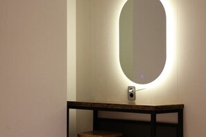 A bathroom with a wall-mounted mirror, a wooden vanity, and a light fixture. - ONU STAY Ikseon (Seoul)