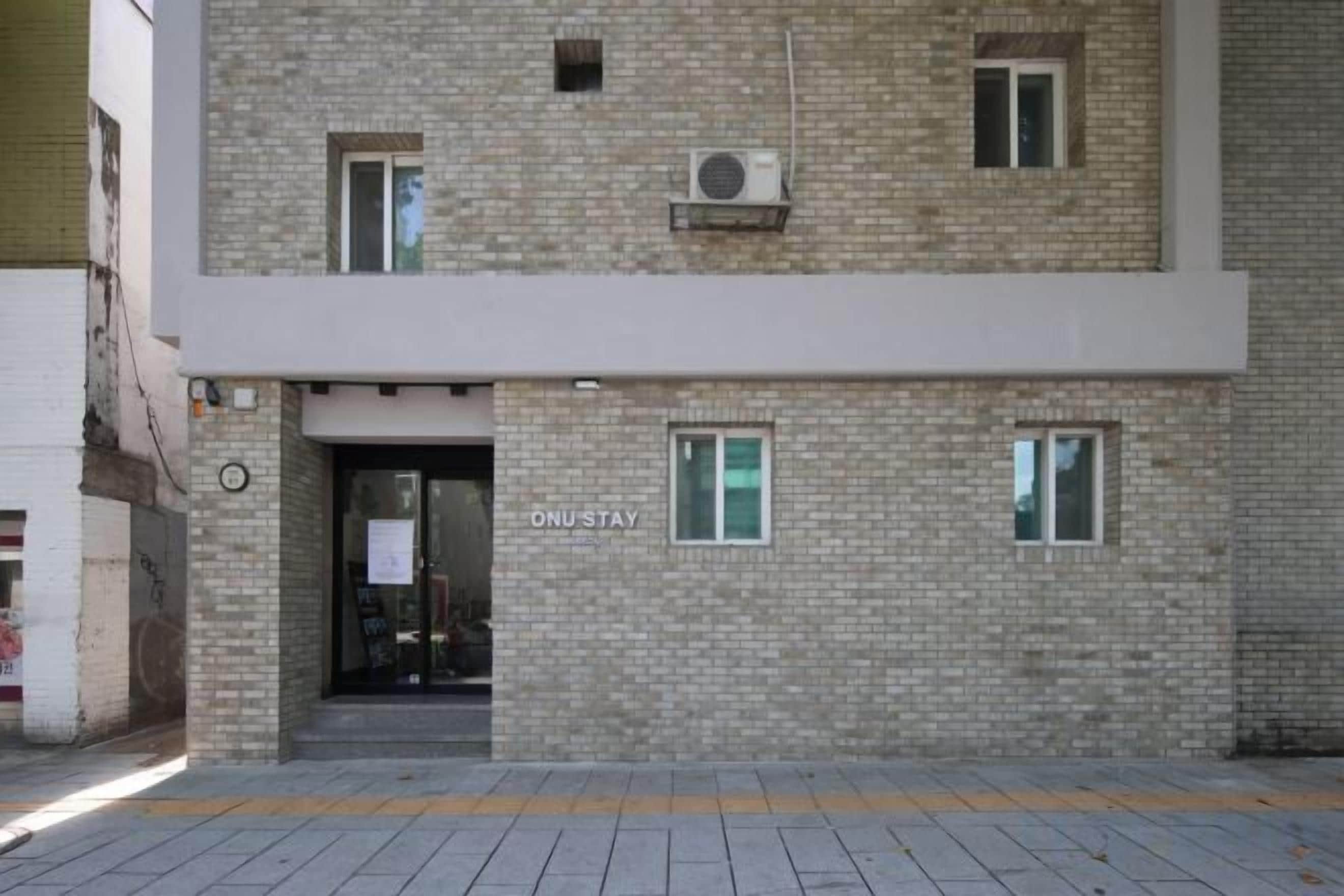 A building with a sign reading 'ONU-STAY' and a brick facade.