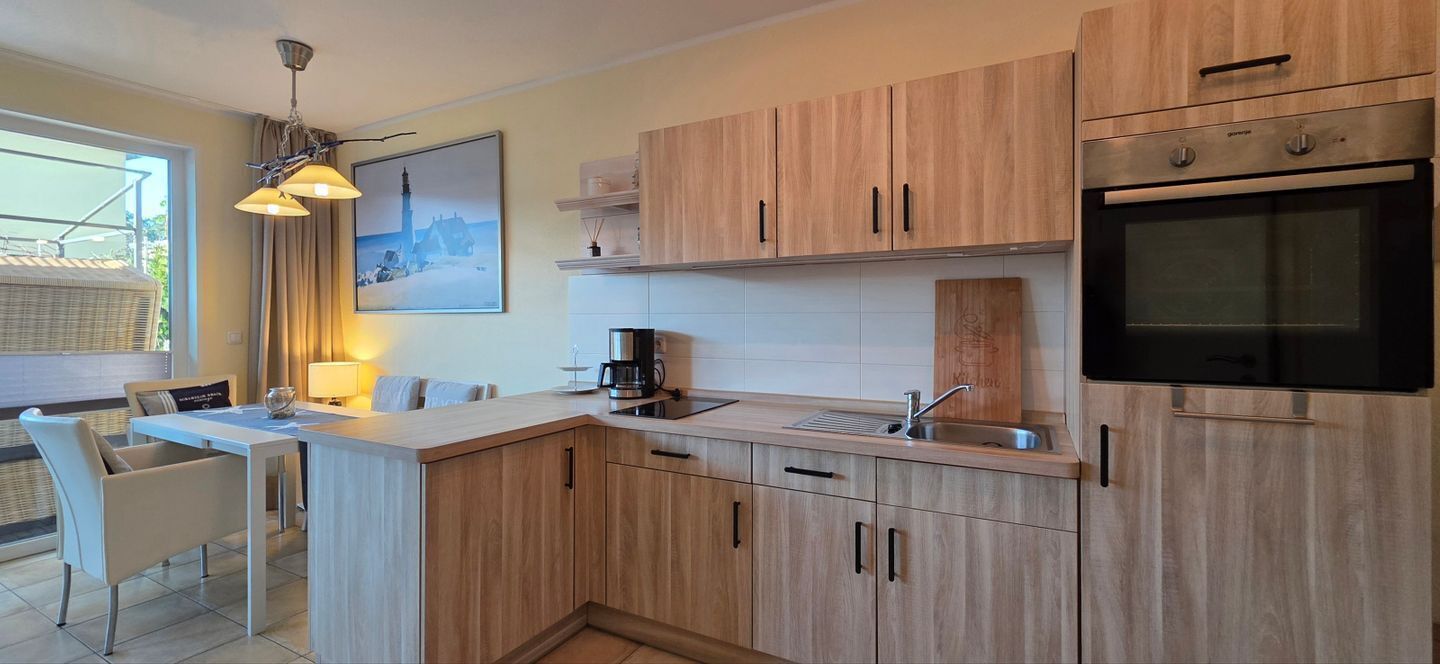 Una cucina moderna con mobili in legno, forno integrato e zona pranzo con tavolo e sedie.