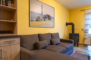 Un salon chaleureux avec un canapé marron, un meuble en bois et un tableau représentant un phare.