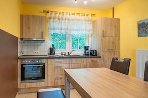 Une cuisine compacte dotée de meubles en bois, d’un four encastré, d’un évier et d’un coin repas avec une table et des chaises.