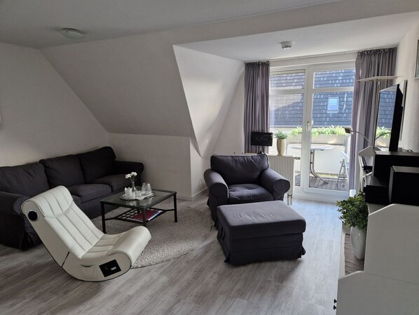 A modern living room with a sofa, a recliner, a coffee table, and a TV stand. - Jordanstr. 35 Whg.5 "Irmgards Meerzeit" - Modern vacation apartment with balcony and (Zingst)