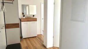 Una cocina moderna con armarios blancos, encimera de madera y un espejo sobre el lavabo.