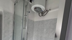 Ein modernes Badezimmer mit einer gläsernen Duschkabine, weißen Fliesen und einer integrierten Toilette.