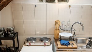 Eine kleine Küche mit einem weißen Brandt-Herd, einer Edelstahl-Spüle und einem Holz-Küchenhelferhalter.