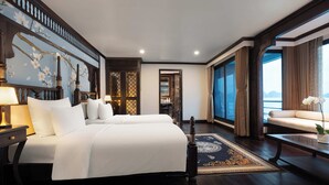 A spacious hotel room with a large bed, a sitting area with a view, and a decorative wall. - Velar Of The Sea Cruise (Tuan Chau)