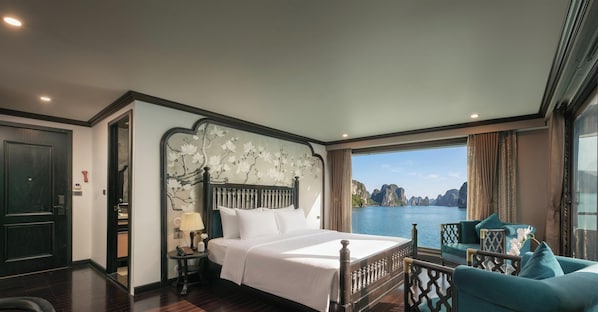 A hotel room with a large bed, a view of a body of water, and a balcony with seating. - Velar Of The Sea Cruise (Tuan Chau)