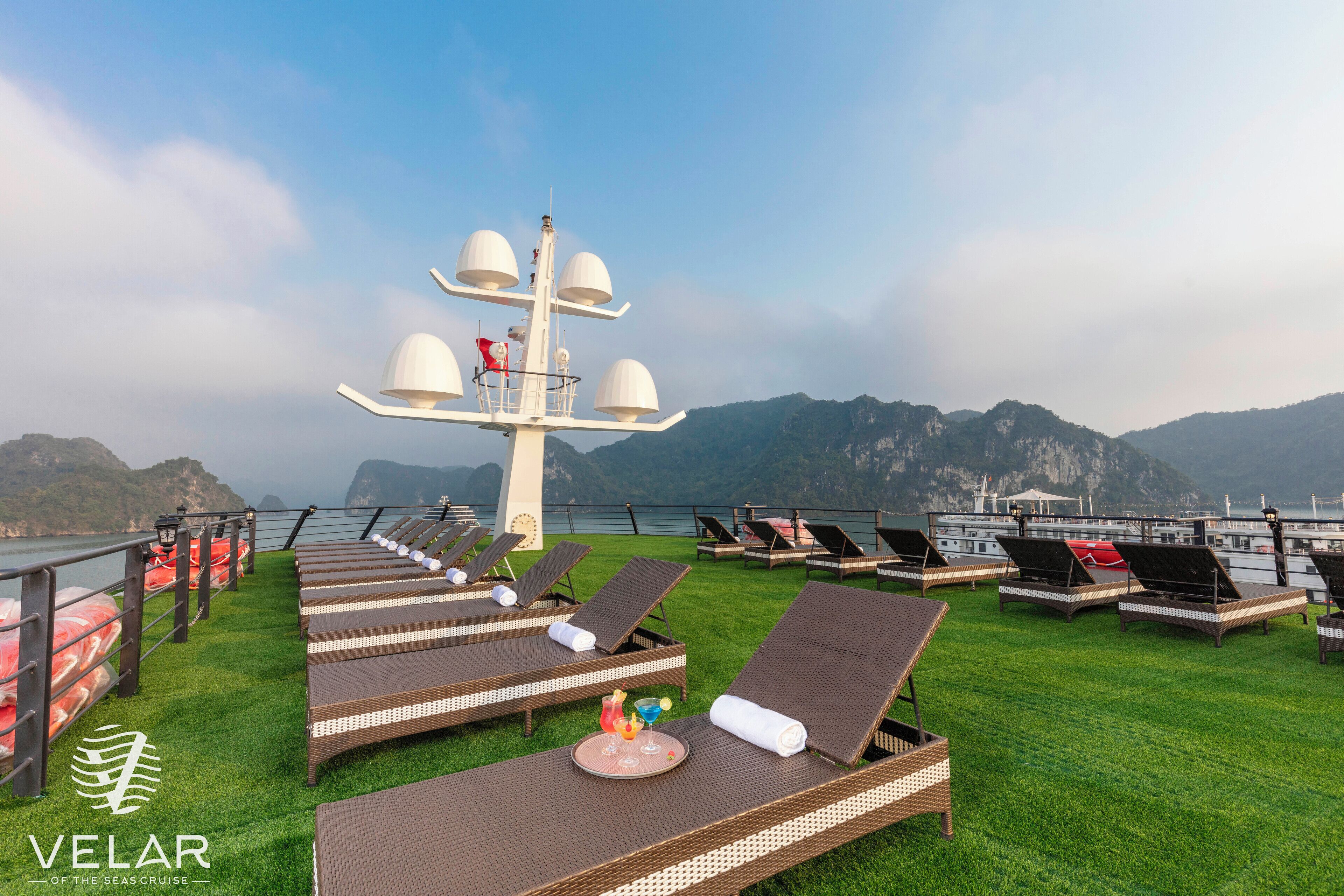 A deck with sun loungers, a buffet table, and a bell tower.
