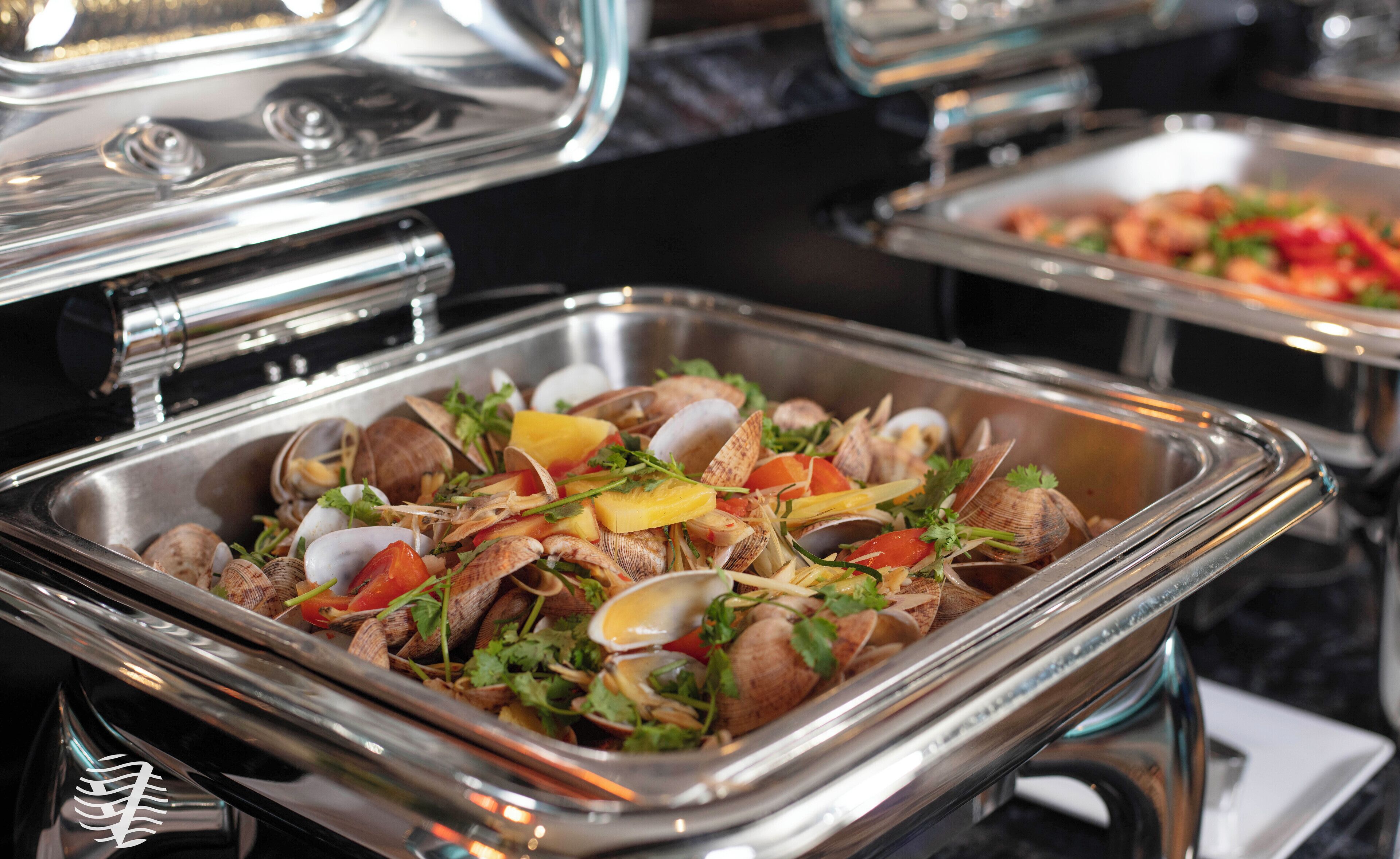 A buffet with various dishes including clams, vegetables, and eggs.