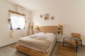Une chambre à coucher avec un lit en bois, une chaise, une table de chevet avec une lampe et des éléments de décoration fixés au mur.