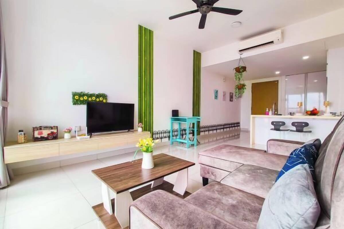 Een moderne woonkamer met een bank, een salontafel, een televisie en een keuken op de achtergrond.