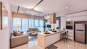 A modern kitchen with a central island, a dining area with a sofa, and a living room with a TV. - Mid Valley Southkey Mosaic by RR JBcity (Plentong)