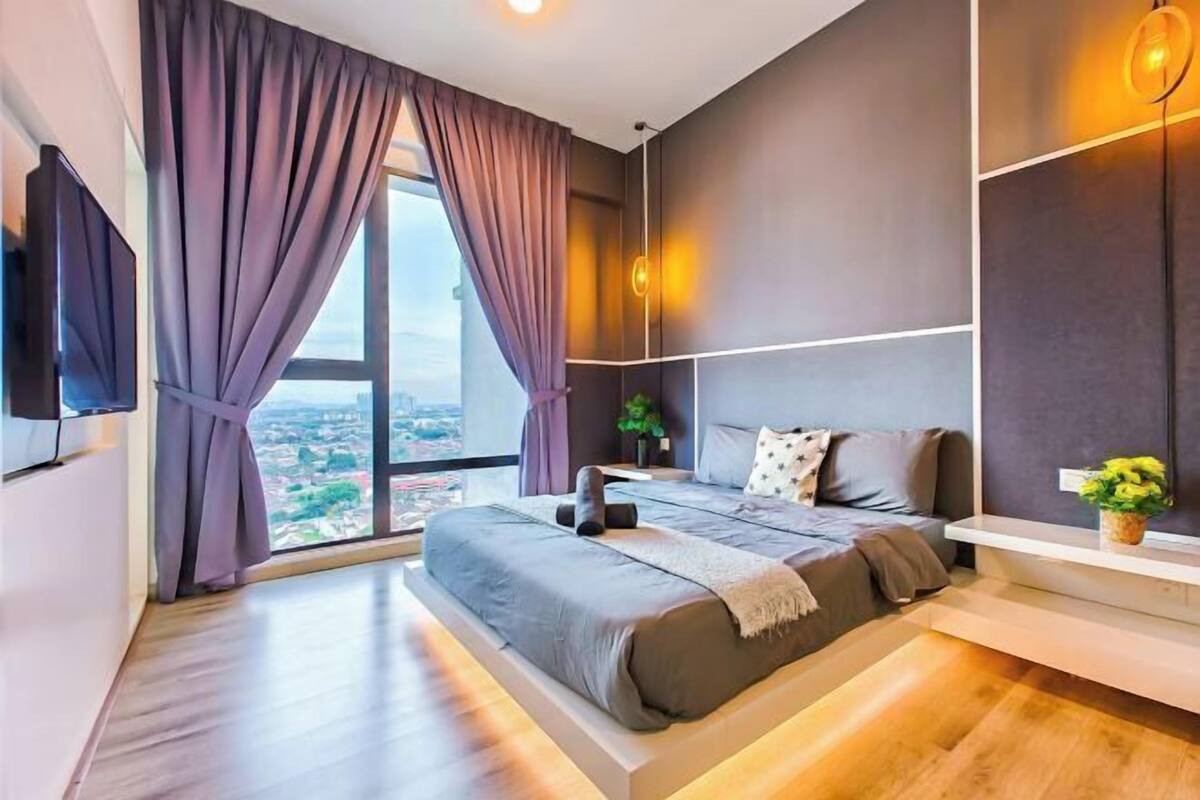 Een moderne slaapkamer met een groot bed, een televisie en uitzicht op de stad.