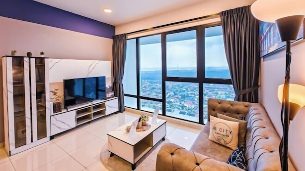 A modern living room with a large window, a sofa, a coffee table, and a TV. - Mid Valley Southkey Mosaic by RR JBcity (Plentong)