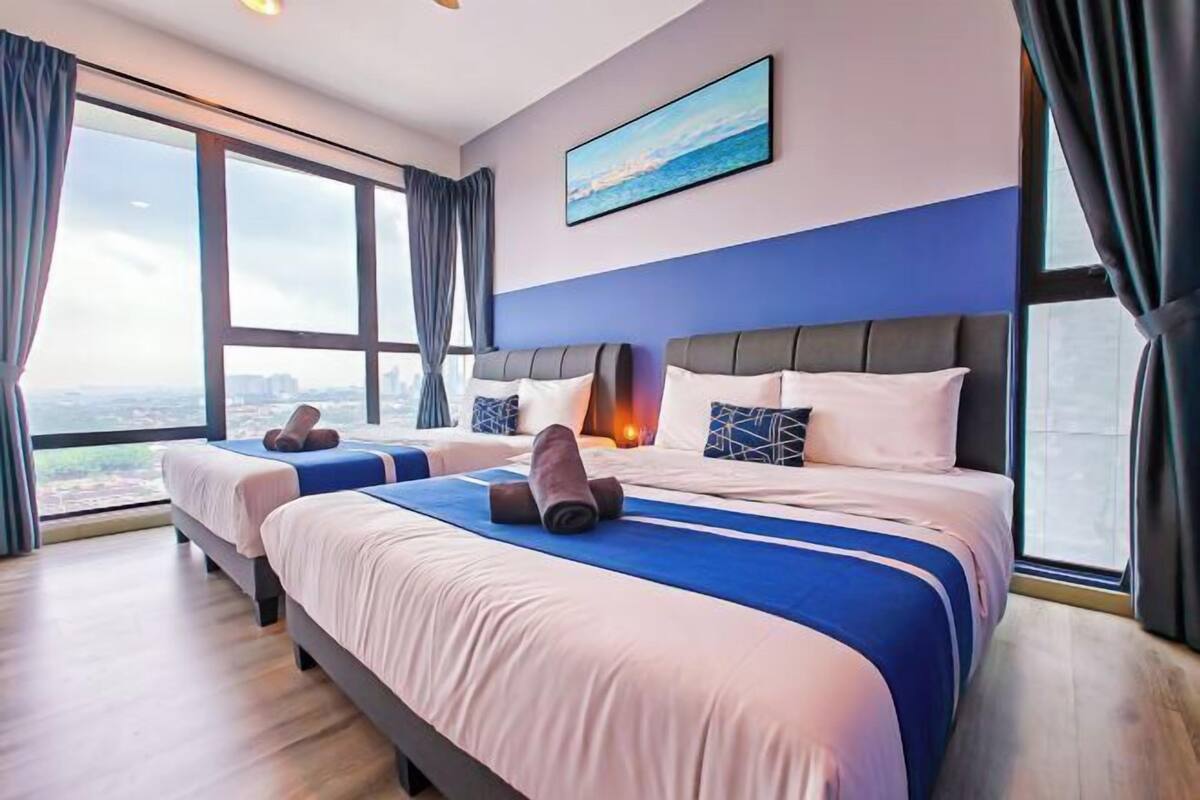 Een hotelkamer met twee bedden, een groot raam en uitzicht op de stad.