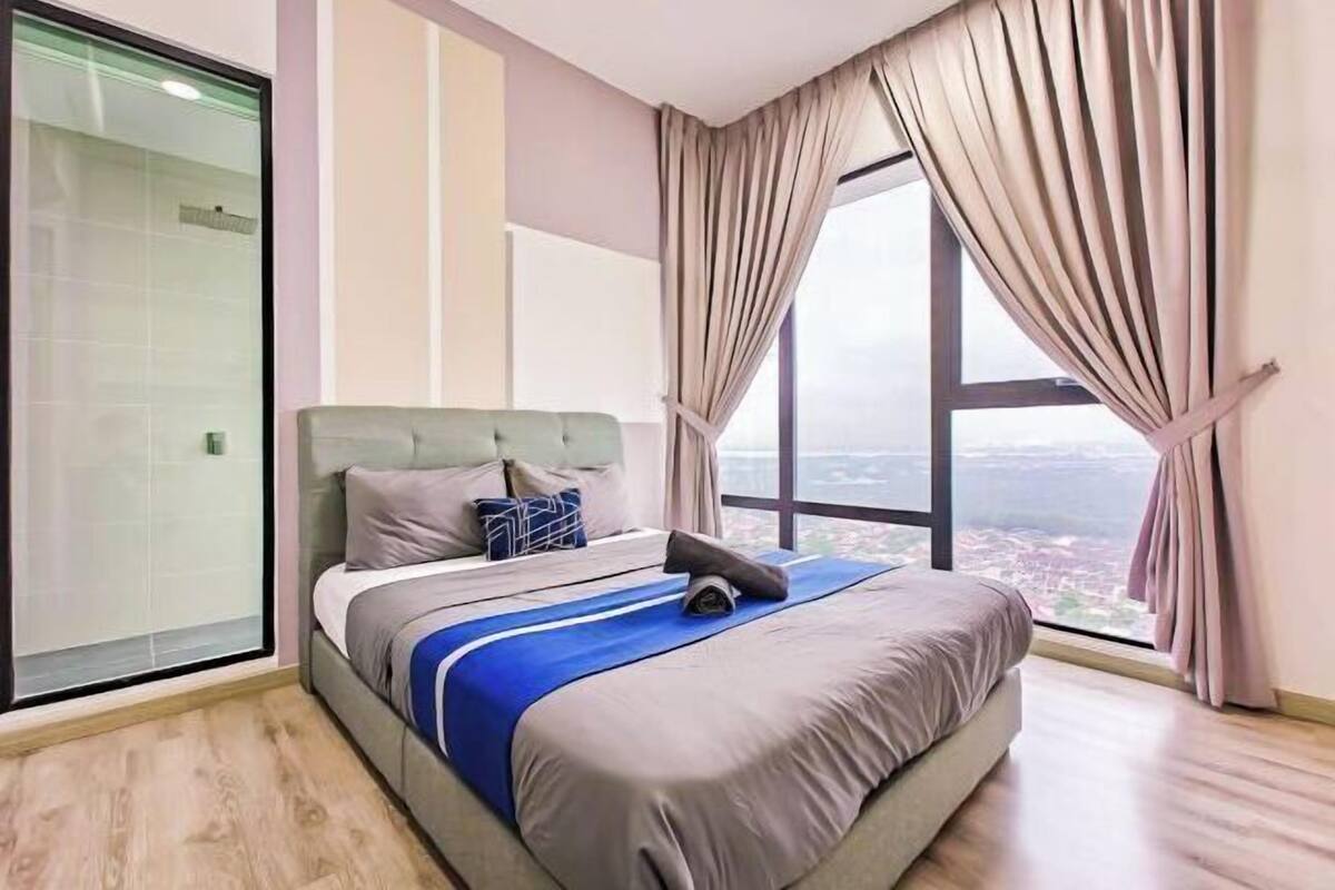 Een moderne hotelkamer met een groot bed, uitzicht op de stad en een glazen deur.