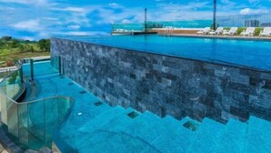 A pool with a glass barrier, a clear blue sky, and a logo for JB City Homestay Resort. - Mid Valley Southkey Mosaic by RR JBcity (Plentong)