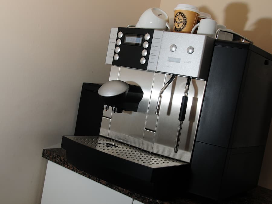 A coffee machine with a digital display, a milk frother, and a coffee cup holder.