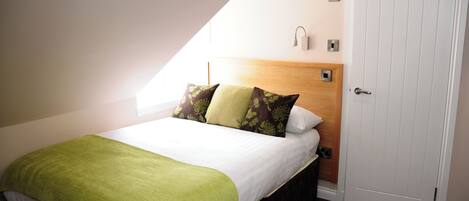 Une chambre à coucher avec un lit, une couverture verte et des coussins à motifs.