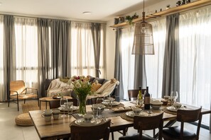 A dining area with a table set for four, a sofa, and a chair. - Luxury Penthouse • Balcony • Parking | HaKerem P2 (680012)