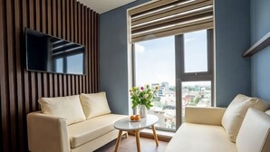 A modern living room with a sofa, a coffee table, and a TV mounted on the wall. - Minh Quan Hotel - Da Nang Center by Hos (Da Nang)