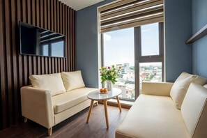 A modern living room with a sofa, a coffee table, and a TV mounted on the wall.