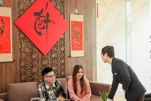 A room with a patterned wall, a red decorative element, and a brown sofa. - Minh Quan Hotel - Da Nang Center by Hos (Da Nang)