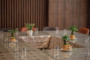 Una mesa de comedor con mantel estampado, plantas en macetas y vasos transparentes.