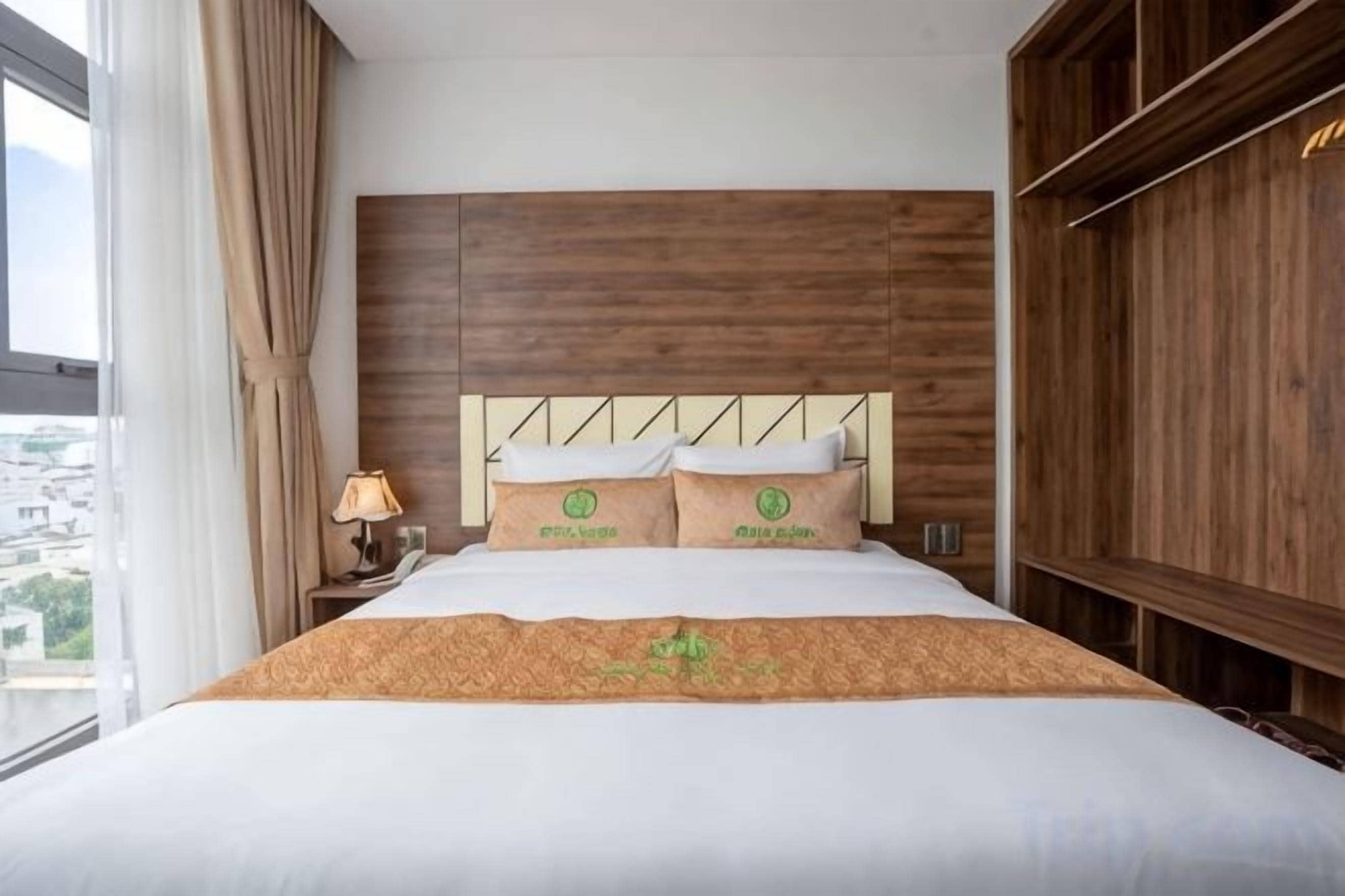 Une chambre d’hôtel avec un grand lit, une tête de lit en bois et une vue par la fenêtre.