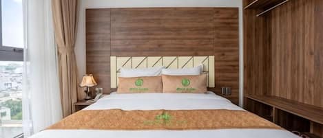 A hotel room with a large bed, wooden headboard, and a view through the window.