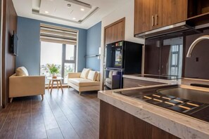 A modern kitchen with a built-in stove, wooden cabinets, and a large window. - Minh Quan Hotel - Da Nang Center by Hos (Da Nang)