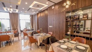A restaurant interior with tables set for dining, a wine display, and a wooden wall with the restaurant's name. - Minh Quan Hotel - Da Nang Center by Hos (Da Nang)