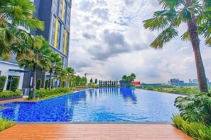 Una piscina con un edificio moderno a un lado y un horizonte urbano al fondo.