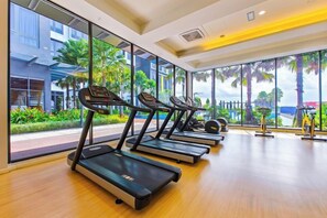 A gym with treadmills aligned against a wall with large windows. - Sunway Grid by RR JBcity (Iskandar Puteri)