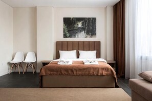 A hotel room with a large bed, two chairs, a nightstand, and a painting on the wall. - Highvill Hotel (Astana)