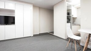 A room with a kitchenette, a white chair, and a small table. - Highvill Hotel (Astana)