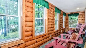 A log cabin with large windows, a wooden deck, and outdoor seating. - Spacious Pet-Friendly Lake Home with 2 Kitchens – Perfect for Family Gatherings (Lac du Flambeau)